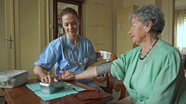 女护士为一位老年妇女测量血压并在探望期间与她交流。视频素材