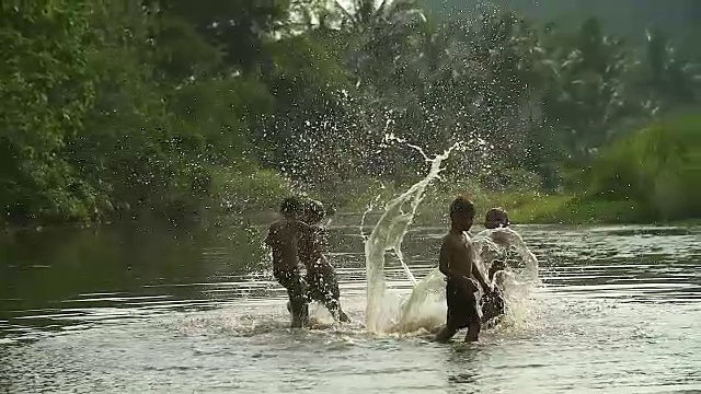 一群小男孩在田里和他的水牛玩水花。展示了亚洲发展中国家的生活方式。视频素材