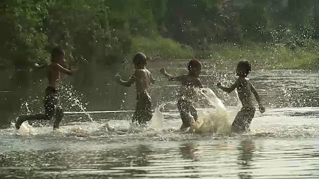 一群小男孩在田里和他的水牛玩水花。展示了亚洲发展中国家的生活方式。视频素材