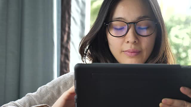 亚洲女性使用和看平板电脑与眼镜，特写视频下载