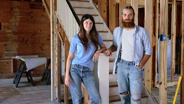 一对幸福的夫妇站在房子装修的楼梯底部视频下载