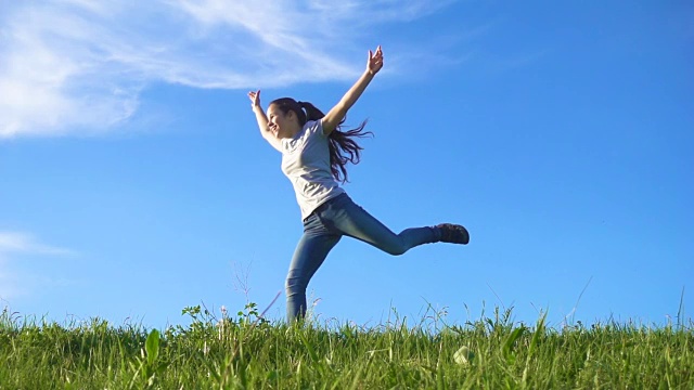 快乐的女孩奔跑在绿色的草山上，对着蓝天视频素材