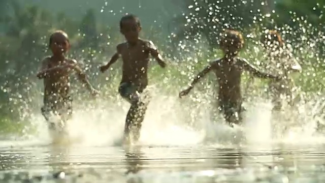 亚洲男孩玩在河与溅水一起玩。(缓慢)视频素材