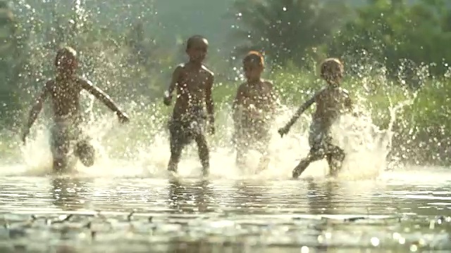 亚洲男孩玩在河与溅水一起玩。(缓慢)视频素材