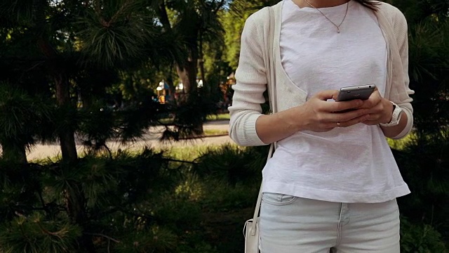 优雅的年轻女子在夏天的公园里享受手机，特写，慢镜头视频下载