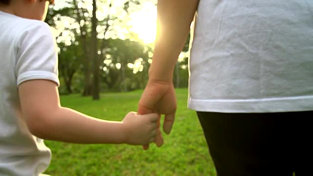 母子手牵着手在公园里散步。视频素材