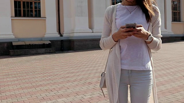 年轻女子在夏天的城市里使用手机，慢镜头视频下载
