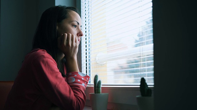 悲伤的女人透过窗户看视频素材