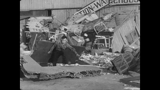 一个男人(巴斯特·基顿饰)穿过一个被毁的剧院的后台门视频素材