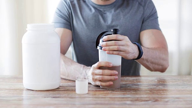 男人在健身跟踪器与罐子和瓶子准备蛋白质奶昔视频素材