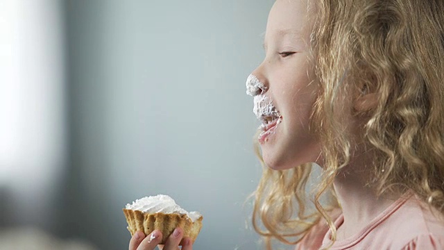 有趣的金发小孩吃着奶油蛋糕笑着，生日派对，糖果棒视频素材