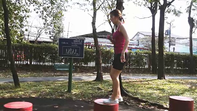 女子在公园的红色方块形状上跳跃的慢动作视频素材