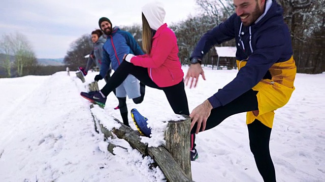 喜欢运动的人们在雪地上做伸展运动。视频素材