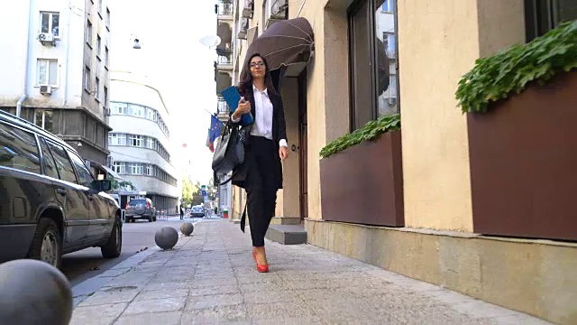 优雅的女人走在街上，手里拿着夹子视频素材