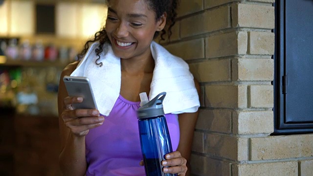 美丽的黑人女子在健身房锻炼完后用智能手机聊天视频素材