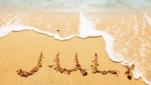 月的名字刻在沙上，沙滩上。视频素材