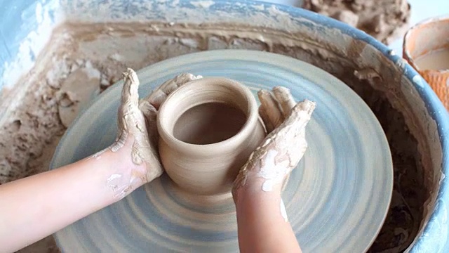 Happy Kid is Pressing a Clay Vase on Wheel, Kid is Working at Pottery Wheel Slowly and Molding a Vase, Blonde Little Girl People Are Making a gift From a Clay, Learning a Pottery Craft .快乐的孩子在车轮上压一个粘土花瓶，孩子在陶器轮缓慢地工作和成型一个花瓶，金发小女孩人们正在从一个粘土做礼物，学习一个陶器工艺视频下载