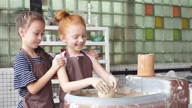 两个小女孩在一个陶轮上玩粘土玩得很开心视频下载