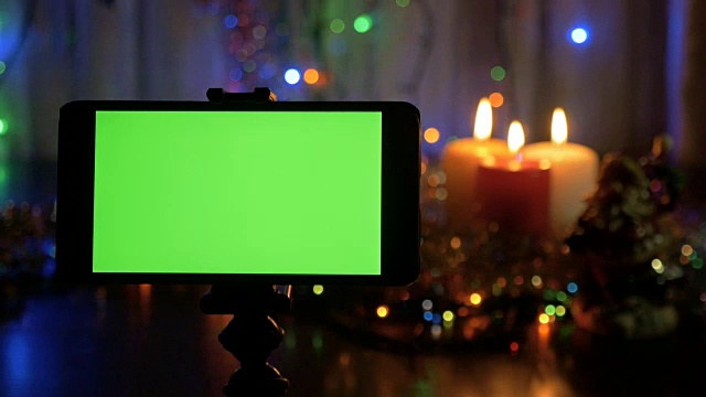 绿色屏幕的智能手机。新年背景模糊了。一个很好的机会添加您的问候视频。视频下载