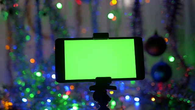 以新年为背景，绿色屏幕的智能手机。照相机围绕物体的运动。视频下载