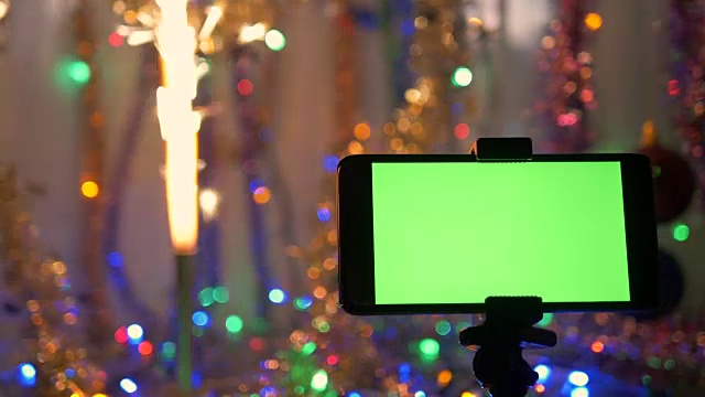 以新年为背景，绿色屏幕的智能手机。节日的烟火在燃烧。视频下载