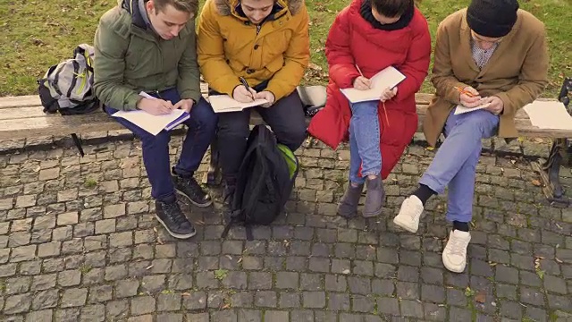 四个学生在笔记本上写字视频下载