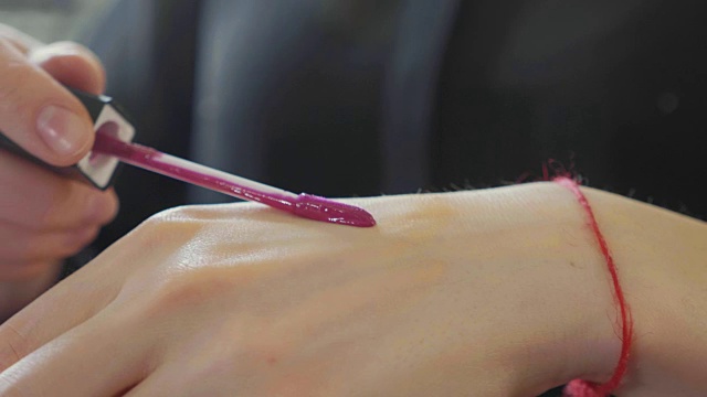 年轻的化妆师在化妆过程中将多余的唇膏涂在手头上视频下载