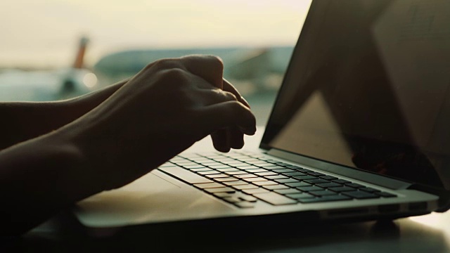 女性用手在笔记本电脑键盘上打字。靠在机场候机厅的窗户上视频下载