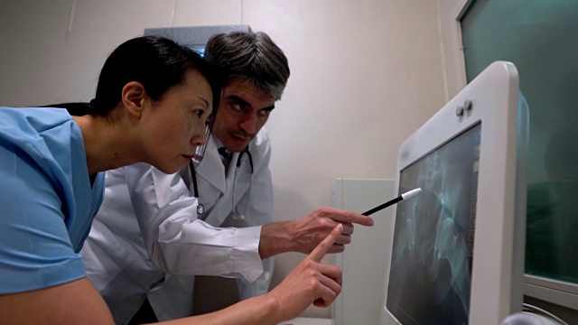 医生和护士看着盆腔x光片指向屏幕视频下载