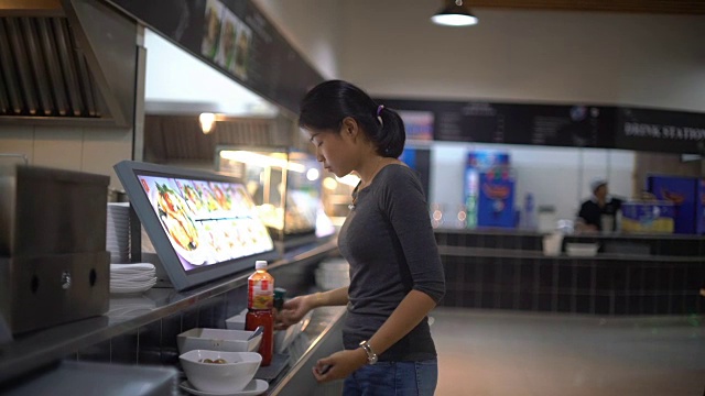 年轻的亚洲女士在美食广场往菜里加香料视频素材
