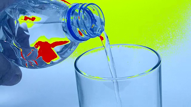 手握水瓶，将水倒入蓝色背景的玻璃杯中视频下载