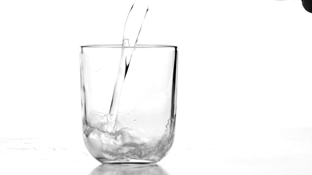 手握水瓶，将水倒入白色背景的玻璃杯中视频下载