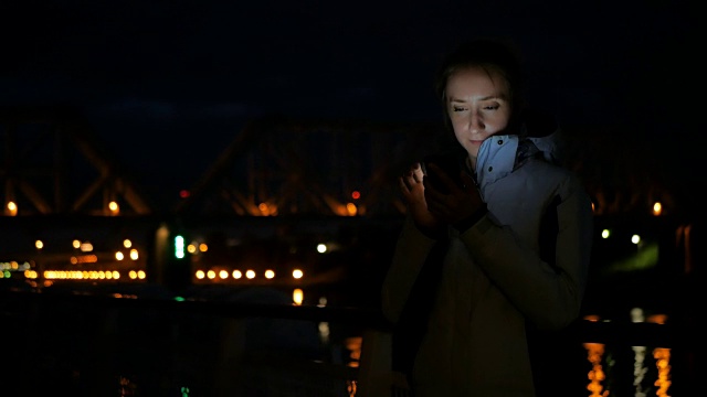 一名女子晚上在游轮甲板上使用垂直智能手机视频素材