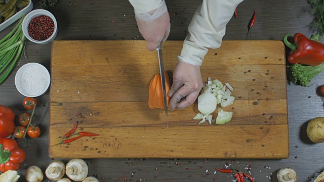 厨师切洋葱和胡萝卜。洋葱和胡萝卜作为汤或其他菜的原料。俯视图视频下载