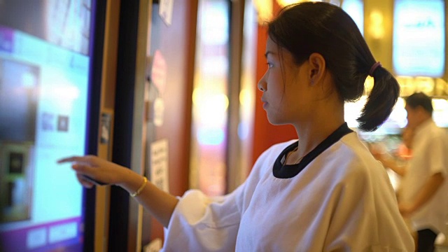 年轻的亚洲女人在电影院使用售票机视频下载