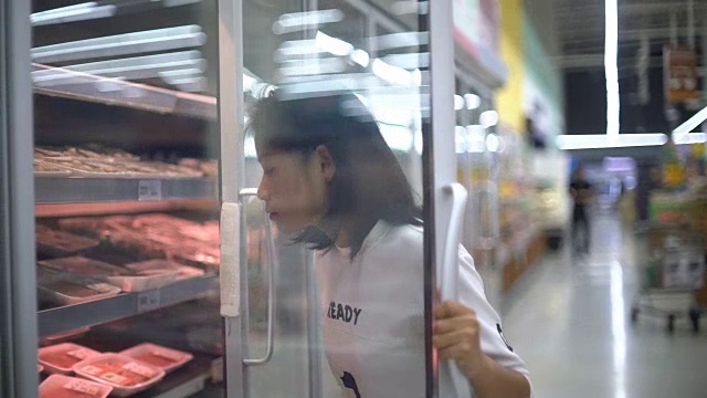年轻的亚洲女人在超市买碎肉视频素材