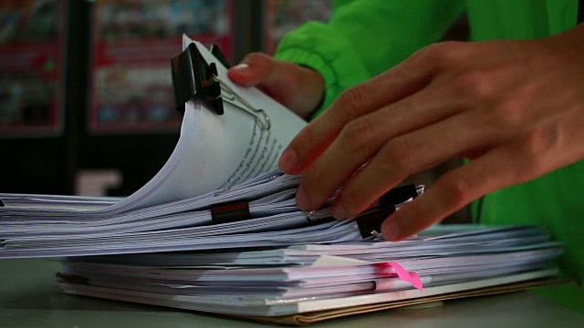 商人的手搜索未完成的文件成堆的文件文件在办公桌上的报告文件，成堆的文件sheet档案与剪辑在桌子上，文件被写，画，提出。视频素材