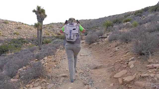 登山妇女步道上山调整她的帽子，后视镜，慢动作视频下载