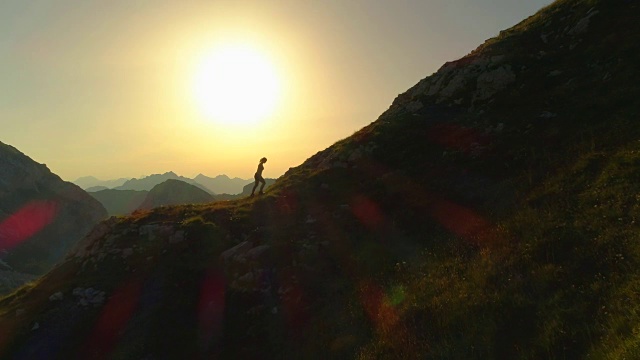 空中剪影拷贝空间:一名年轻女子在黄昏时分爬上山坡。视频素材