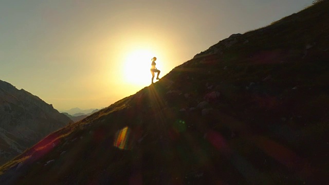 空中剪影:女徒步者试图在日落前到达山顶。视频素材