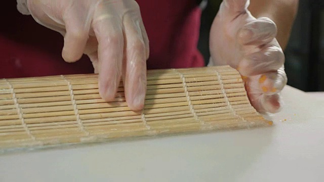 专业寿司厨师在商业厨房准备寿司卷，特写。视频素材