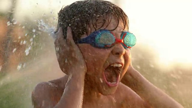 电影慢镜头，60帧每秒，4k分辨率，一个孩子尖叫着，耳朵捂住了双手，被水淹没了视频素材