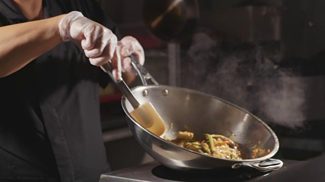 特写厨师烹饪面条与肉和蔬菜在锅视频下载