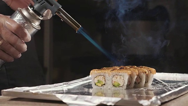 专业寿司厨师准备通过火在商业厨房，特写。视频素材