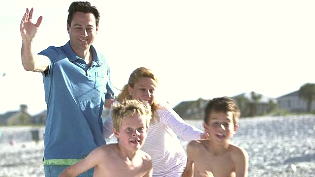 两个男孩在海滩上得到父母的拥抱视频素材