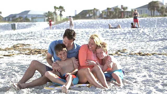 两个男孩在海滩上得到父母的拥抱视频素材