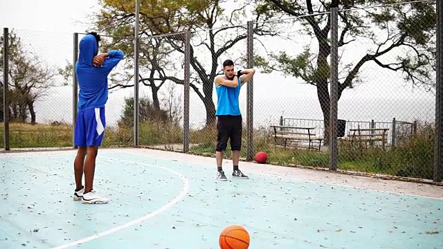 两个年轻的朋友在街上打篮球前热身。Slowmotion拍摄视频下载