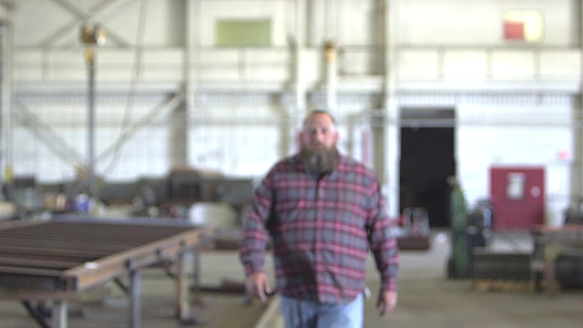 仓库里留着胡子的大个子男人走向摄像机视频素材