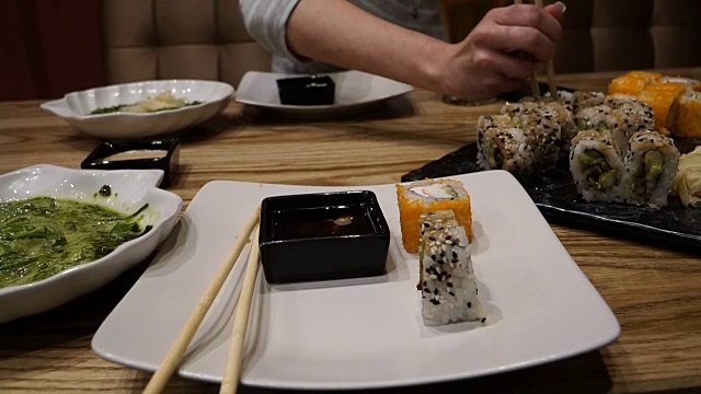 一个女孩在寿司店吃寿司，喝啤酒视频素材