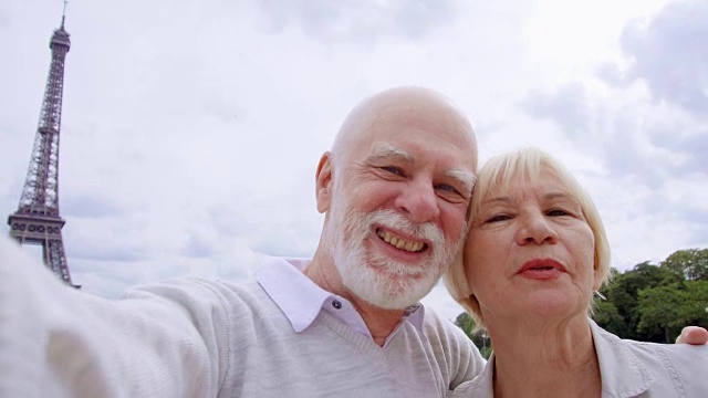 一对老夫妇在埃菲尔铁塔附近自拍。在欧洲旅游。退休后活跃的现代生活视频素材